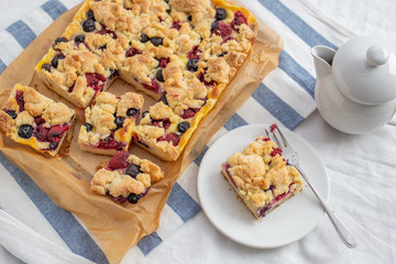 Sweet delicious crumble cake in a baking form and pieces of the cake on a table