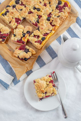 Sweet delicious crumble cake in a baking form and pieces of the cake on a table