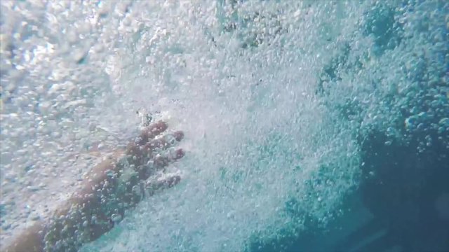 Underwater air bubbles in swimming pool, go pro view of man's hand