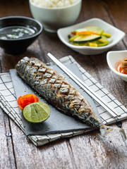 One set of saba grill serve with slide dish, kimchi, rice and seaweed soup with korean style serve menu on wood table.