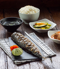 One set of saba grill serve with slide dish, kimchi, rice and seaweed soup with korean style serve menu on wood table.