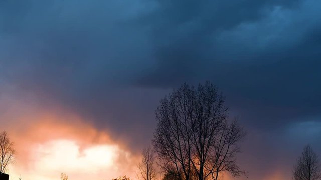 Bright sunset or sunrise on a dark sky with thunderclouds. Sunset or sunrise with dark clouds and sunlight , against the light 