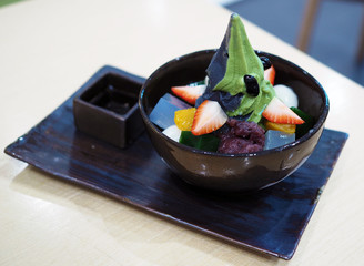 Two tone soft served ice cream, matcha and charcoal served in black bowl decorated with fresh strawberry, orange, mochi and red bean, Healthy eating concept, selective focus. 