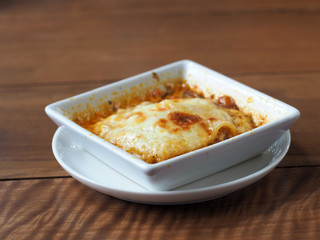 Baked spinach with cheese on wooden table.