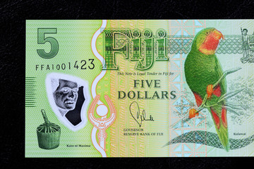 Five Fijian dollars banknote on a dark background close up