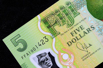 Five Fijian dollars banknote on a dark background close up