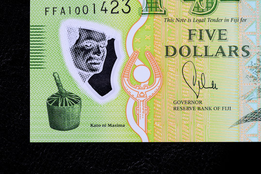 Five Fijian dollars banknote on a dark background close up