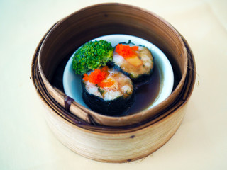 Bamboo basket of Steamed minced prawn wrapped with seaweed topped with crab roe, Chinese traditional food style. Selective focus.