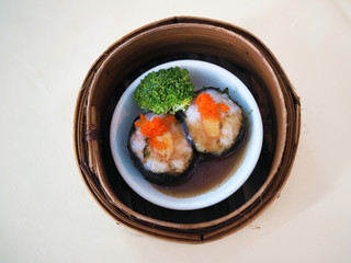 Bamboo basket of Steamed minced prawn wrapped with seaweed topped with crab roe, Chinese traditional food style. Selective focus.