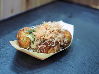 Japanese cook has made Takoyaki for tourist. Takoyaki is a ball-shaped Japanese snack made of a wheat flour-based batter and cooked in a special molded pan.