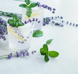 Lavender lemonade with lemon , mint, ice cubs, lavender flowers on blue background. Detox water, summer drink.  Top view. Copy space