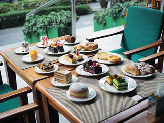 Variety of homemade bakery such as strawberry fresh cream cake, chocolate fudge cake, tart, croissant, bread and roll on the table