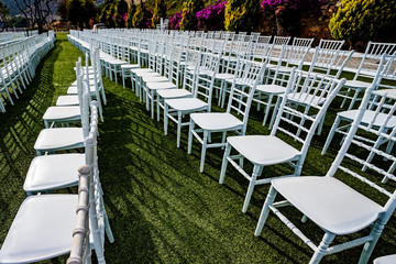 A green field with white chairs and tables. Place for wedding ceremonies.