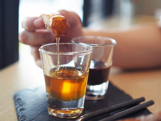 Dipping traditional Spanish dessert churros  with organic honey served on black stone tray.