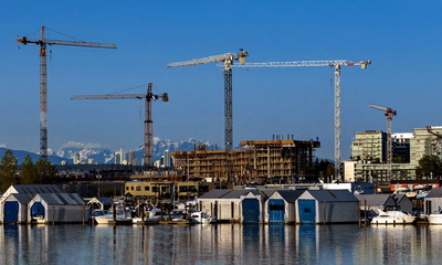 Fototapeta na wymiar Construction of a new high-rise buildings in the city side of the riverbank in city of Vancouver