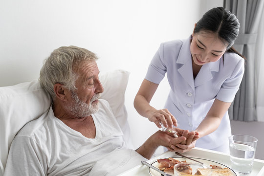 nurse give pill to senior man after breakfast and discussion on bed at nursing home