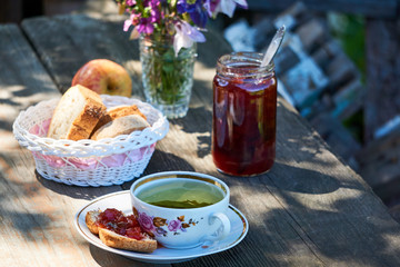 Herbal tea with plum jam and bread on a wooden table