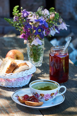 Herbal tea with plum jam and bread on a wooden table