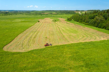 Naklejka premium Aerial view on the countryside and the tractor mows the grass