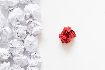 Independence concept. Flat lay of crumpled same color paper ball pile against different red one. White background. Copy space.