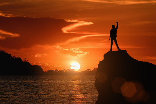 One man is holding a fist, happy with success, looking at the sunset.Silhouette image.