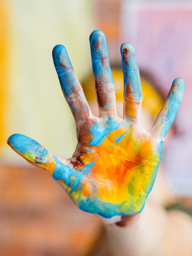 Finger Painting Art Trend. Closeup Of Blue And Yellow Colored Hand. Blur Background.