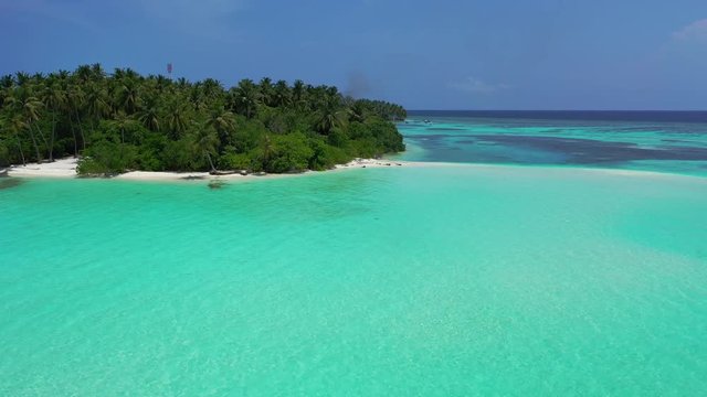 Aerial view of an island with turquoise greenish water in front of it. The Caribbean.  Dolly in