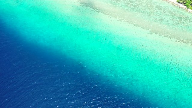 Looking down while flying above a water divide in the Maldivian Sea. Shallow turquoise turns into a deep blue.