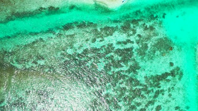 Aerial perspective looking down on a reef in turquoise blue water. The Philippine Sea. Circular pedestal up, wide angle.