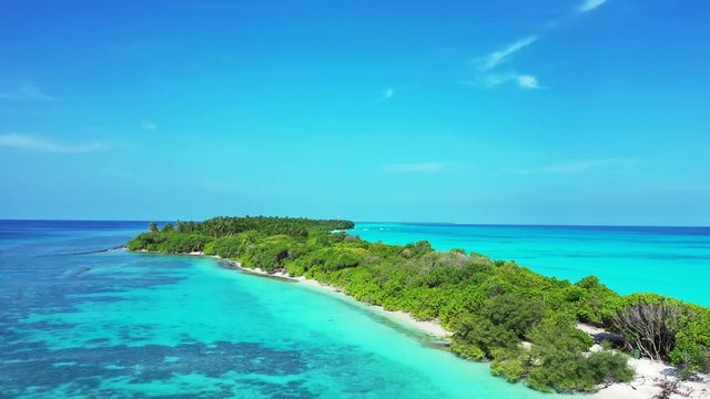 Aerial view of a tropical island forested. In the turquoise Caribbea Sea. Truck right, pan left.