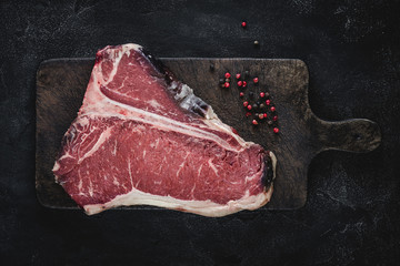 Raw T-bone Steak Dry Aged for Grill or BBQ on Vintage Cutting Board