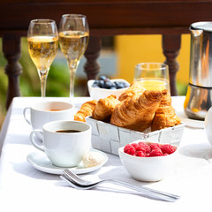 Luxury brunch on the hotel  terrace, coffee maker, teapot, cups, croissants, fruits, orange juice...