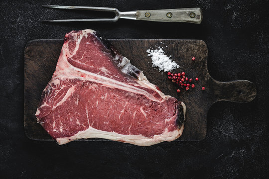 T-bone Steak Raw Dry Aged Beef on Vintage Cutting Board