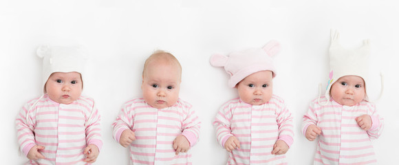 Cute adorable baby child with different warm white and pink hats. Happy baby girl on white background and looking at the camera.