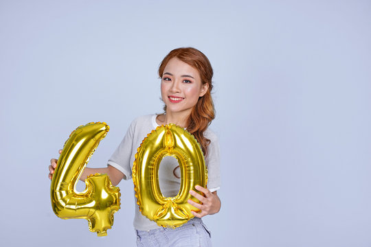 Asian young attractive beautiful young girl holding metallic foil balloon number