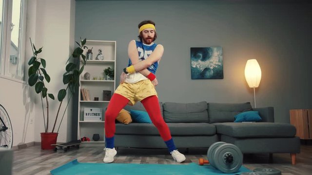 Funny young bearded sportsman dancing with cool energetic moves warming up and exercising at home.
