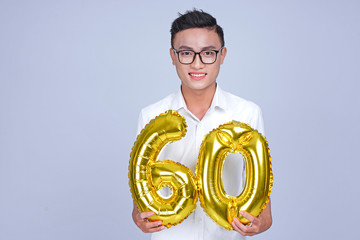 Asian young handsome attractive male student holding metallic foil balloon with number