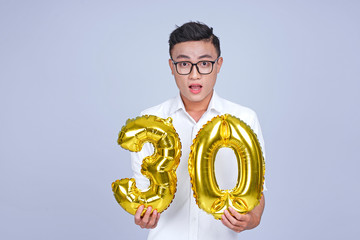 Asian young handsome attractive male student holding metallic foil balloon with number