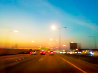 On the expressway, there are colorful lights and evening sky. With lots of cars and trucks.