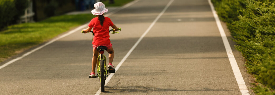 Children Learning To Drive A Bicycle On A Driveway Outside. Little Girls Riding Bikes On Asphalt Road In The City