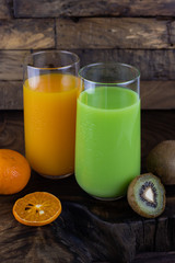 Fresh healthy orange, kiwi juice, smoothie in a glass on wooden background. summer concept.
