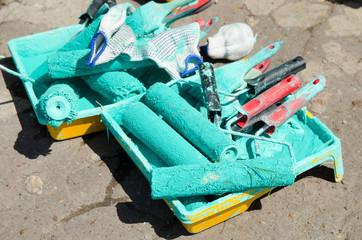 several paint rollers covered with green paint are in the tray