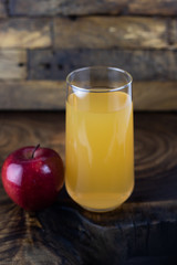still life photo of apple juice in glass on wooden background.
