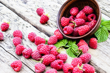 Ripe red raspberries on a bowl on the background of old boards. Selective focus.
