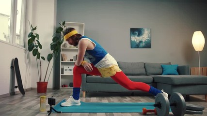 Confident strong retro fitness man doing sports exercise on the mat. Athletic man stretching and training at home.