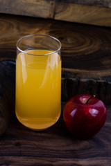 still life photo of apple juice in glass on wooden background.