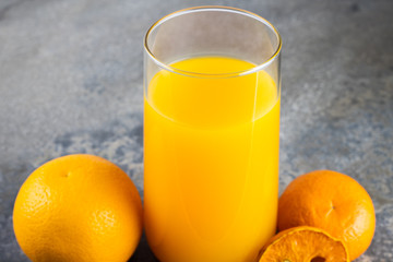 still life photo of orange juice, orange smoothie in glass on concrete background.