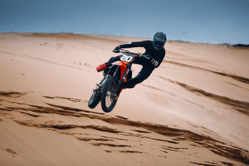 Motorcyclist on a cross-country motorcycle jump from the sand dune