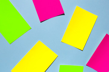 Neon colorful sticky note paper on blue background. Copy space for your text. Flat lay, top view. 