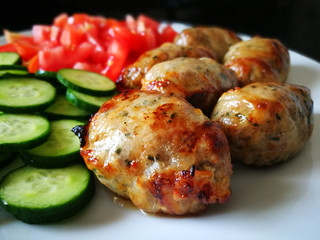 Grilled Sausages with Fresh Vegetables (Cucumber and Tomato) on a White Plate. Traditional Cypriot food: Sheftalia : Cypriot Lamb and Pork Sausages. 